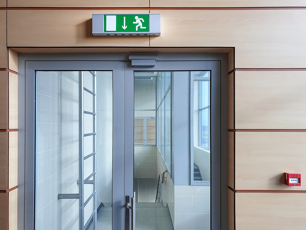Emergency exit with glass door in airport office building. Emergency fire doors. Rescue signs icon green emergency exit lamp