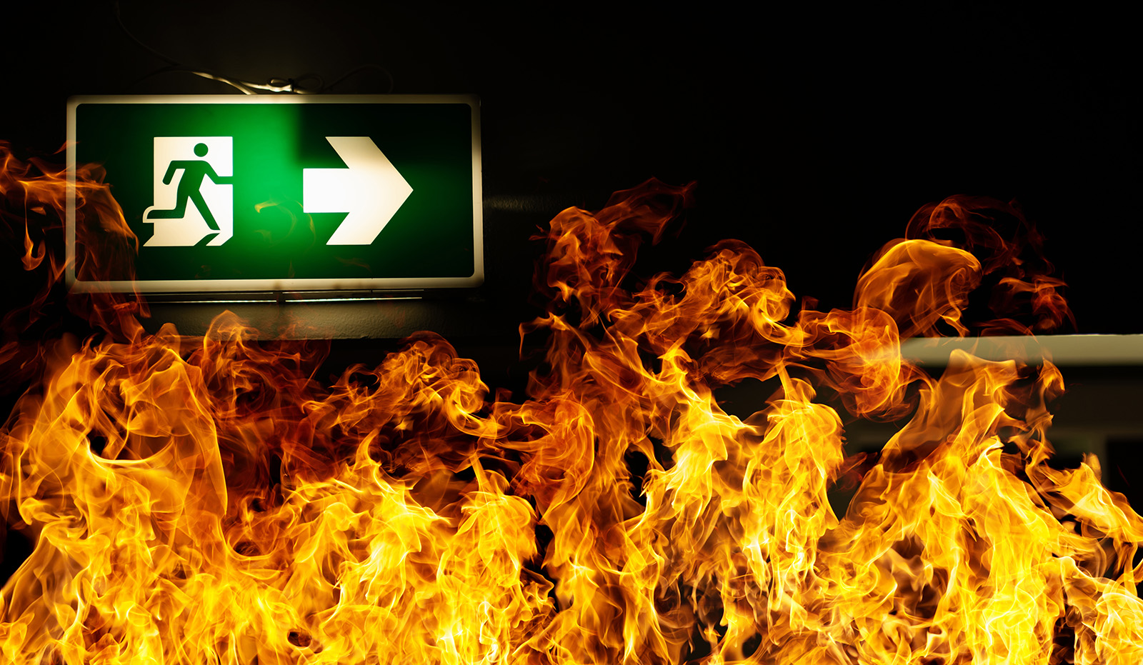 Green fire escape sign hang on the ceiling in the Warehouse. The concept of fire escape training and preparation for evacuation